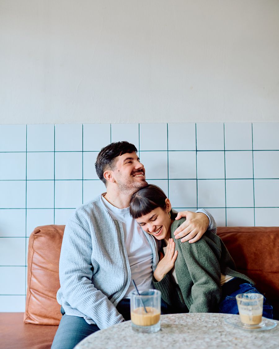 A couple laughing together over coffee at a local café